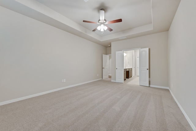 spare room featuring a tray ceiling, ceiling fan, and light colored carpet