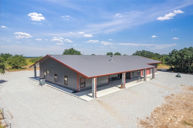 view of front of home with gravel driveway, an attached carport, and metal roof