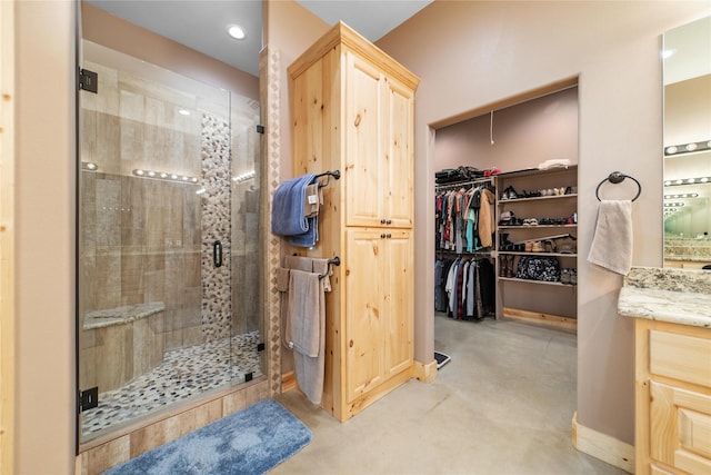 full bathroom with vanity, a spacious closet, finished concrete flooring, and a shower stall