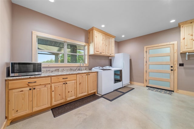 kitchen with stainless steel microwave, light brown cabinets, independent washer and dryer, and a sink