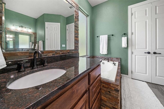 bathroom featuring a bath, vanity, visible vents, and plenty of natural light