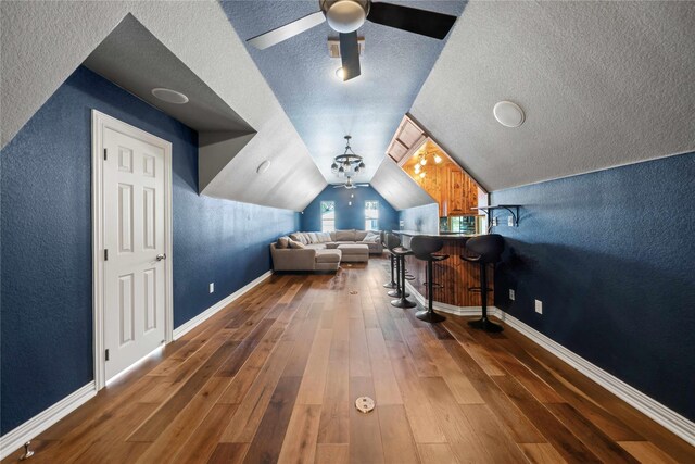 bonus room featuring a textured wall, wood finished floors, a textured ceiling, and ceiling fan