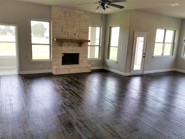 unfurnished living room with a wealth of natural light, a fireplace, ceiling fan, and dark wood-type flooring