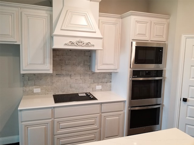 kitchen with premium range hood, backsplash, white cabinets, and stainless steel appliances