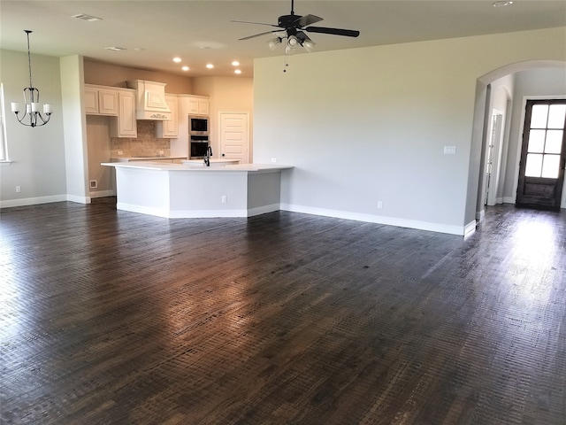 unfurnished living room with dark hardwood / wood-style floors and ceiling fan with notable chandelier