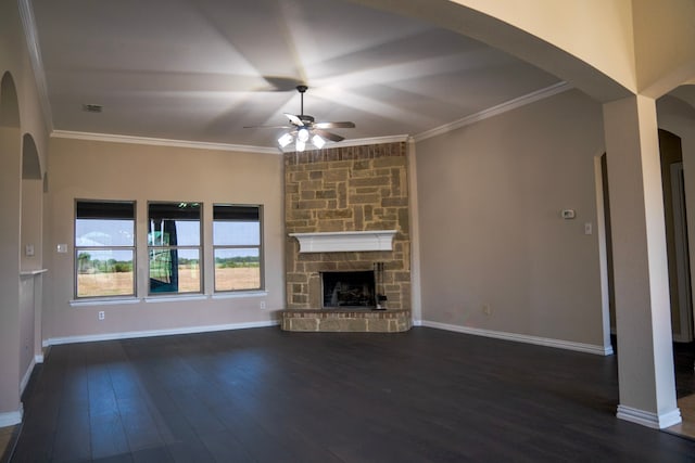 unfurnished living room featuring dark hardwood / wood-style flooring, ceiling fan, ornamental molding, and a stone fireplace