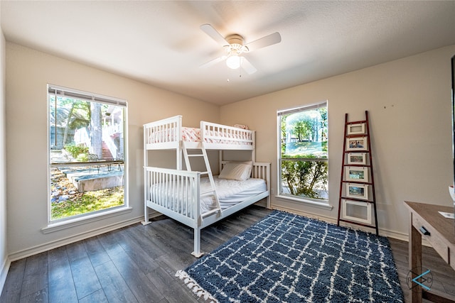 unfurnished bedroom featuring multiple windows, dark hardwood / wood-style flooring, and ceiling fan