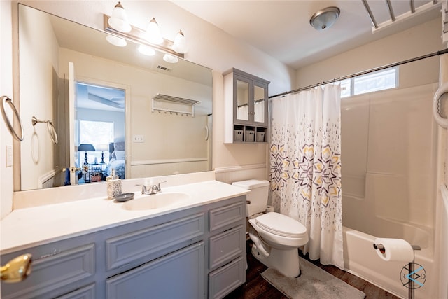 full bathroom featuring hardwood / wood-style flooring, vanity, shower / tub combo with curtain, and toilet