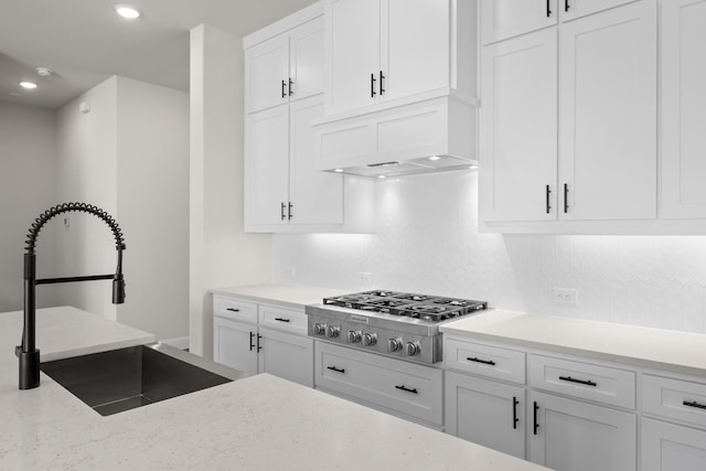 kitchen featuring sink, stainless steel gas stovetop, white cabinets, and custom range hood