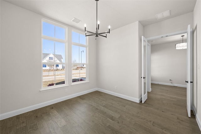 unfurnished dining area featuring a chandelier and dark hardwood / wood-style floors