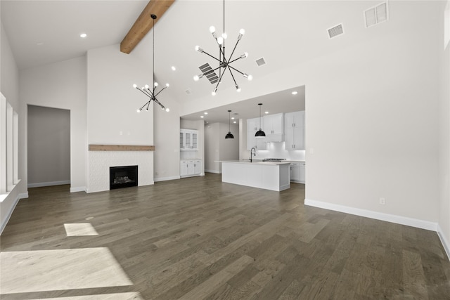 unfurnished living room featuring dark wood-type flooring, a tile fireplace, high vaulted ceiling, beam ceiling, and sink