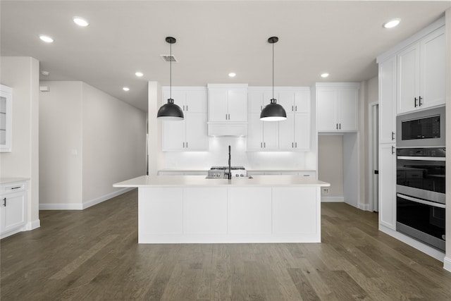 kitchen with hanging light fixtures, white cabinetry, and a center island with sink