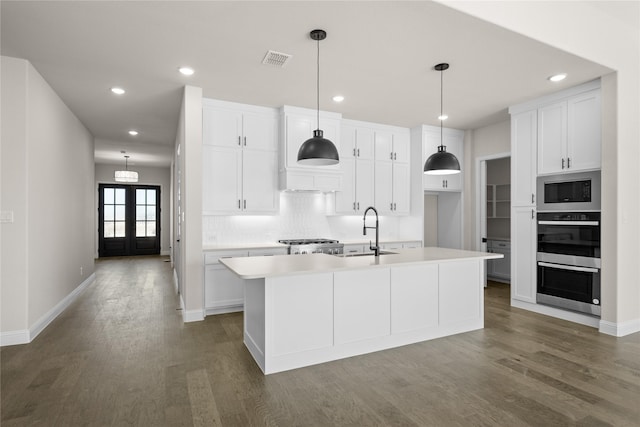 kitchen featuring a center island with sink, white cabinets, french doors, and built in microwave