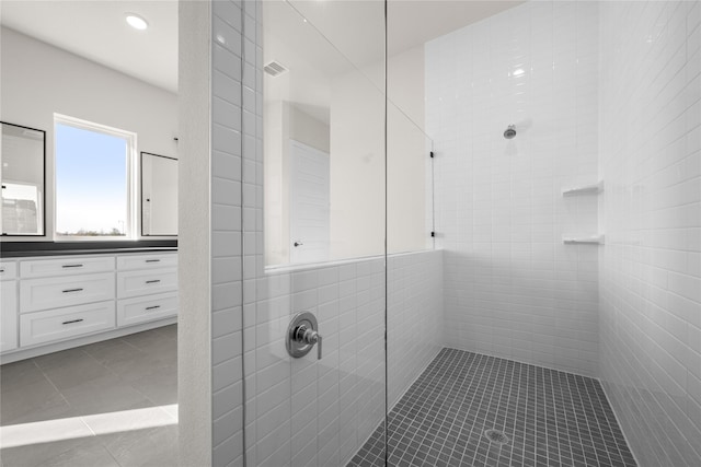 bathroom with a tile shower, tile patterned flooring, and vanity