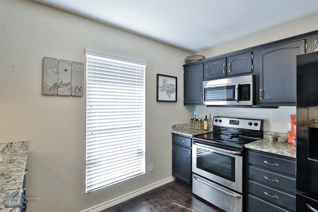 kitchen with dark wood-type flooring, appliances with stainless steel finishes, and light stone countertops