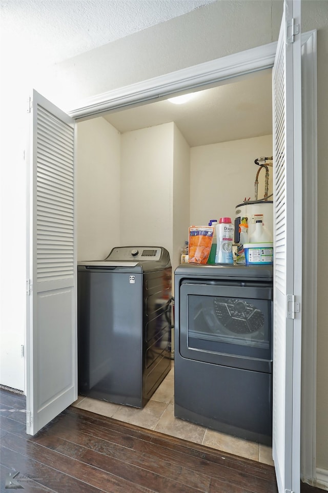 laundry area with wood-type flooring, a textured ceiling, washer and clothes dryer, and electric water heater