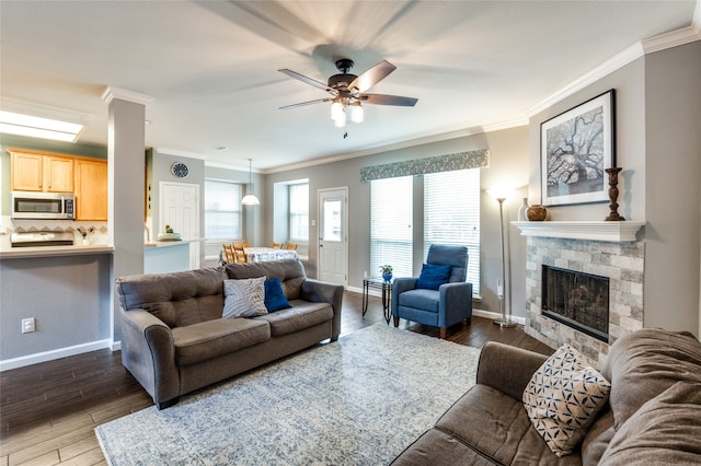 living room featuring ornamental molding, ceiling fan, dark hardwood / wood-style floors, and a stone fireplace