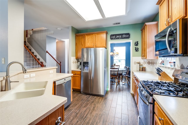 kitchen featuring decorative backsplash, dark wood-type flooring, stainless steel appliances, sink, and a chandelier