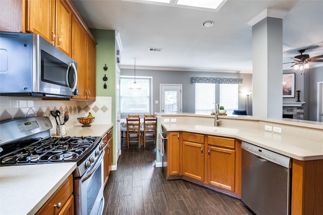 kitchen with appliances with stainless steel finishes, hanging light fixtures, dark hardwood / wood-style flooring, crown molding, and sink