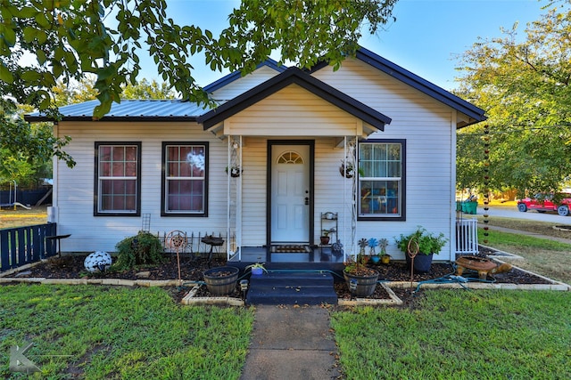 bungalow-style home with a front yard, fence, and metal roof