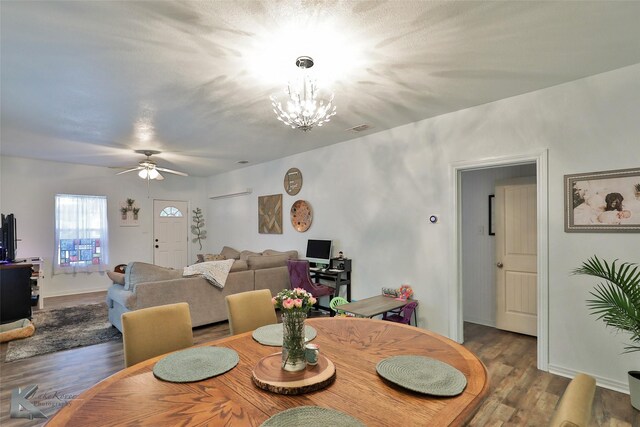 dining area with ceiling fan with notable chandelier and hardwood / wood-style floors