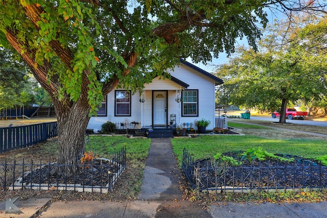 bungalow-style house featuring a front lawn and fence