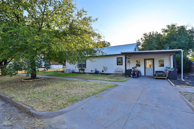 ranch-style home with cooling unit, metal roof, and a front yard