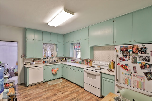 kitchen featuring light wood-type flooring, sink, white appliances, and green cabinets