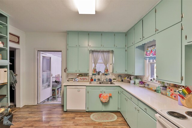 kitchen featuring white appliances, wood-type flooring, green cabinetry, and sink