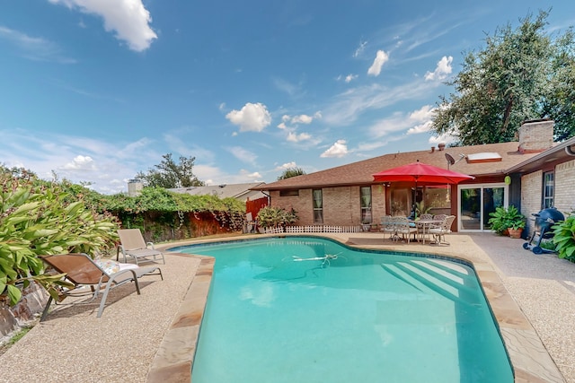 view of pool with area for grilling and a patio