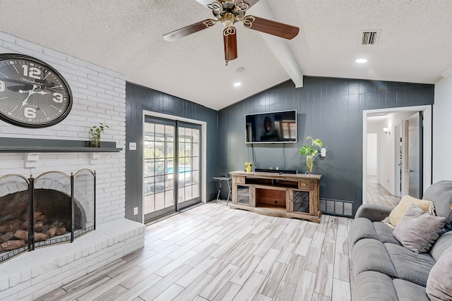 living room with a textured ceiling, light wood-type flooring, wood walls, and a fireplace