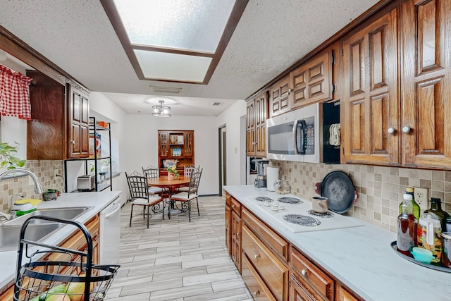 kitchen with a textured ceiling, sink, decorative backsplash, and white appliances