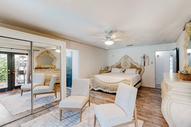 bedroom featuring a textured ceiling, ceiling fan, light hardwood / wood-style floors, and french doors