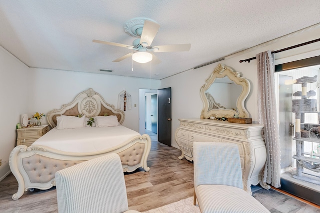 bedroom with a textured ceiling, ceiling fan, and light hardwood / wood-style floors