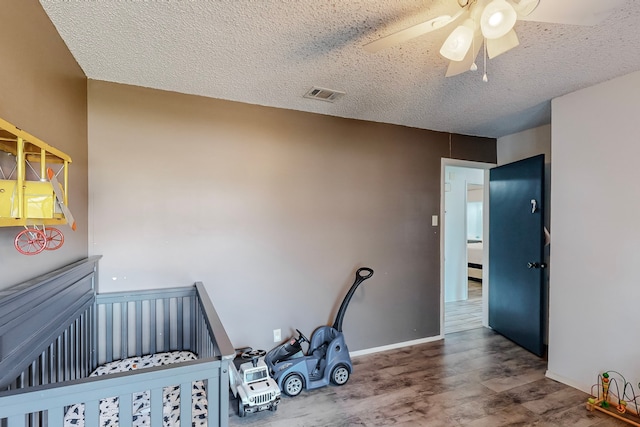 bedroom featuring ceiling fan, a nursery area, and a textured ceiling