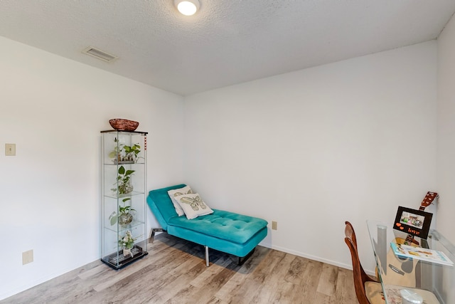 living area featuring light hardwood / wood-style floors and a textured ceiling