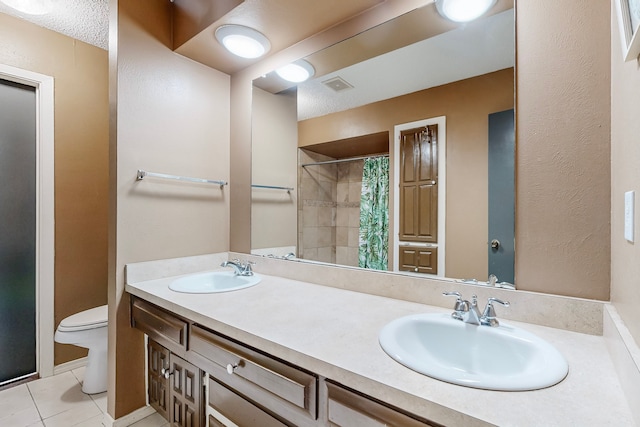 bathroom featuring toilet, vanity, walk in shower, and tile patterned flooring