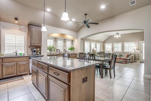 kitchen featuring dark stone counters, a center island, ceiling fan, and lofted ceiling