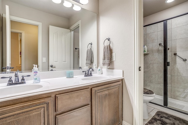 bathroom featuring tile patterned flooring, a shower with door, toilet, and dual bowl vanity