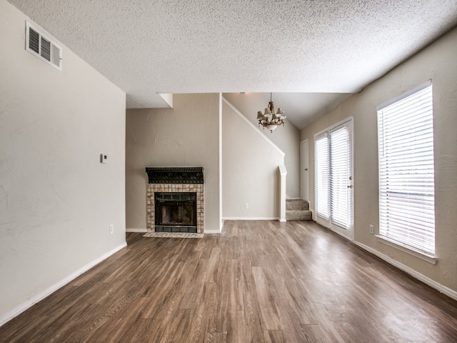 unfurnished living room with hardwood / wood-style floors, an inviting chandelier, and a textured ceiling