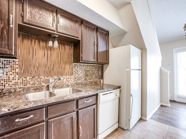 kitchen featuring tasteful backsplash, light hardwood / wood-style floors, white dishwasher, sink, and a textured ceiling