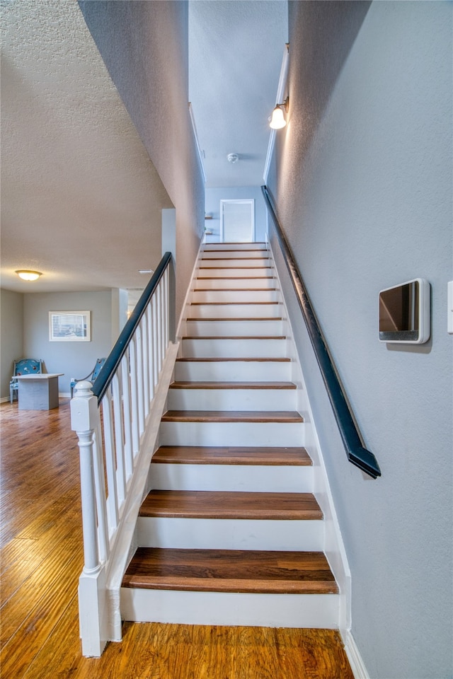 stairway featuring hardwood / wood-style floors and a textured ceiling