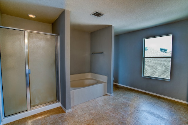 bathroom with a textured ceiling, shower with separate bathtub, and tile patterned floors