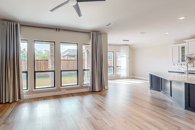 unfurnished living room with a wealth of natural light, light hardwood / wood-style floors, and ceiling fan