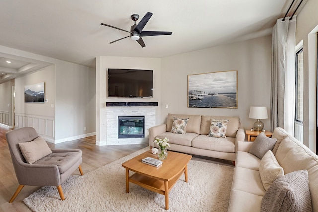 living room featuring a fireplace, ceiling fan, and light wood-type flooring