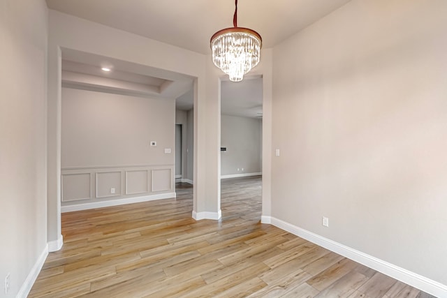 unfurnished room with an inviting chandelier and light wood-type flooring