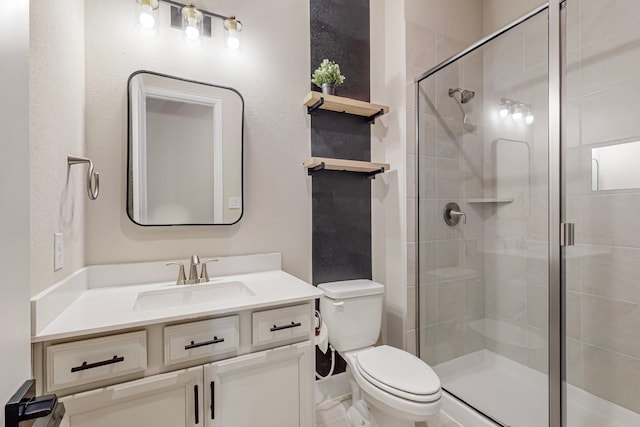 bathroom with toilet, vanity, and a shower with shower door