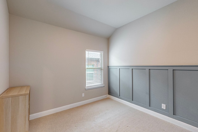 empty room featuring light colored carpet and vaulted ceiling