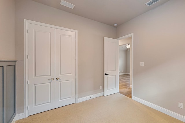 unfurnished bedroom featuring light colored carpet and a closet