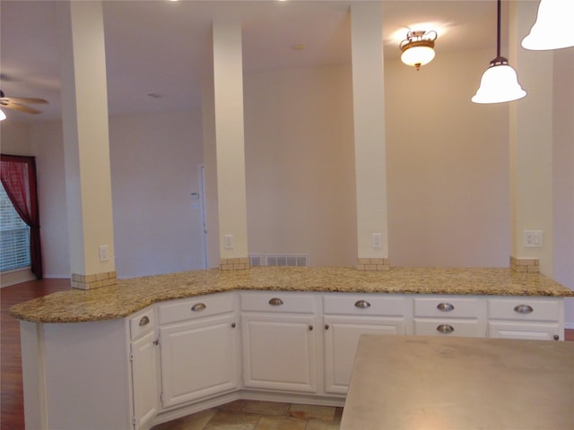 kitchen with pendant lighting, kitchen peninsula, white cabinets, light stone counters, and ceiling fan